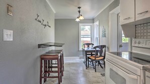 A kitchen with a white stove, a dining table with chairs, and a hanging light fixture. - Rapid City Home w/ Patio by Canyon Lake Park! (Rapid City)