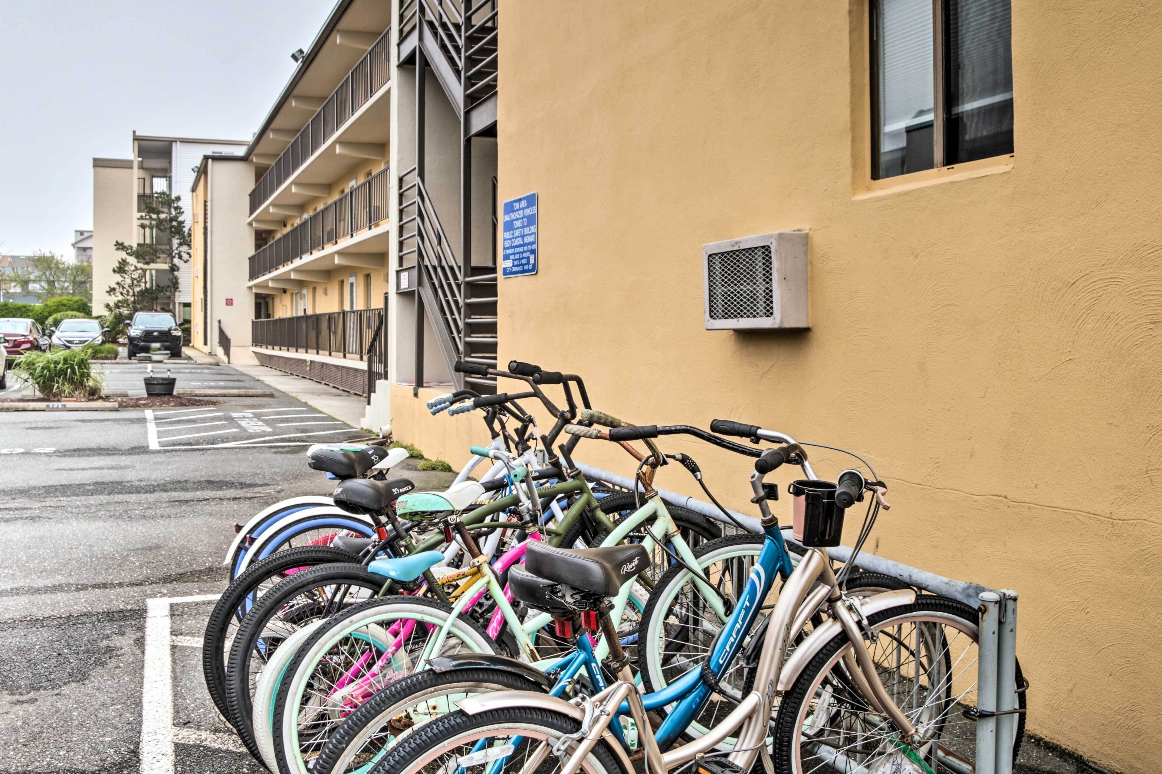 Una fila de bicicletas estacionadas frente a un edificio con un letrero azul en la pared.