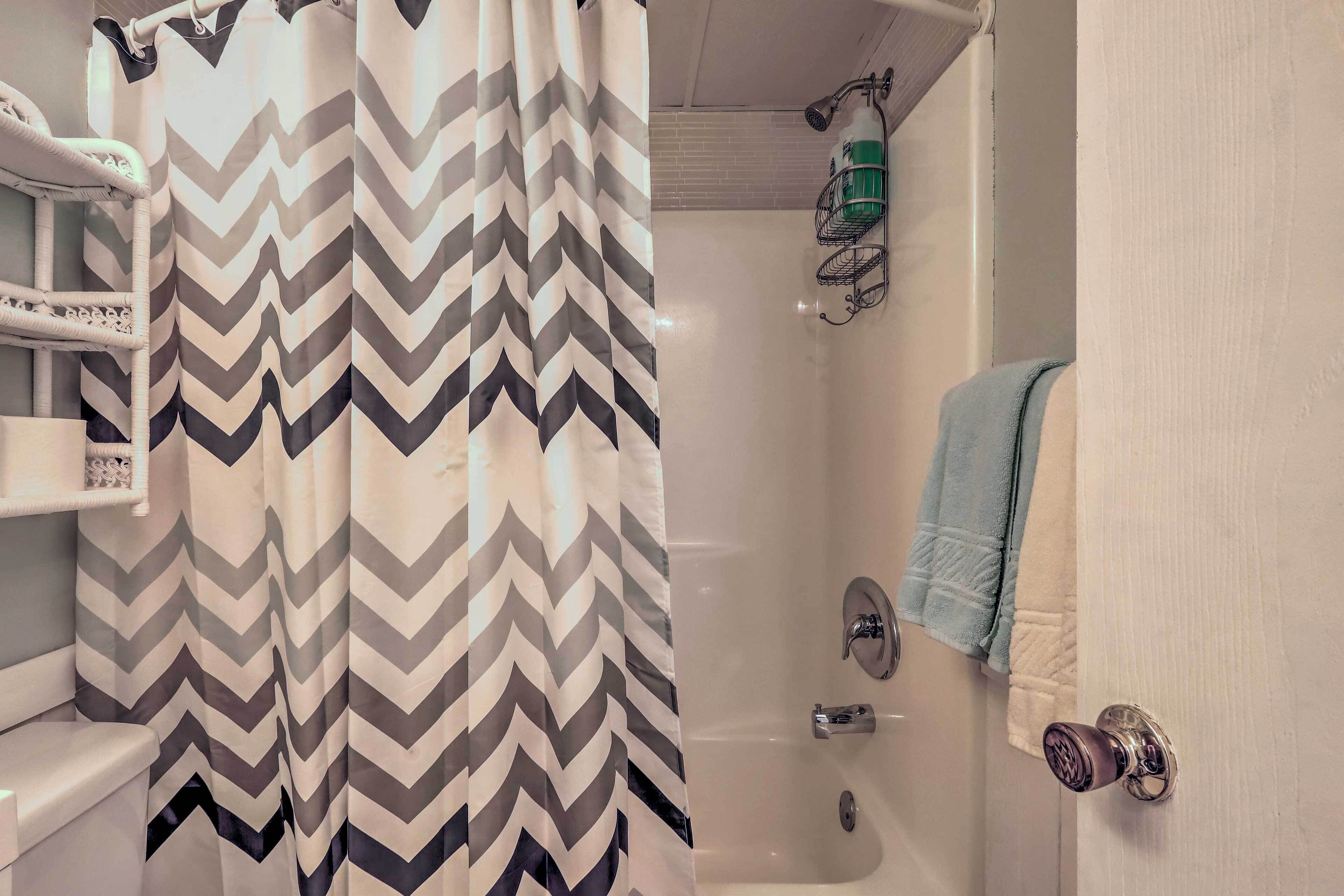 A bathroom with a shower curtain, a toilet, a sink, a towel rack, and a door lock.