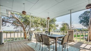 An outdoor patio with a wooden deck, a table with chairs, and a view of the landscape. - Serene Hill Country Wildlife Sanctuary w/ Porch (Boerne)