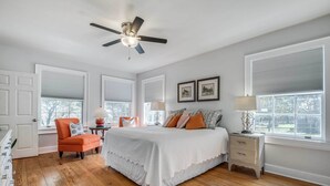 A bedroom with a bed, a chair, a nightstand, and a ceiling fan. - Serene Hill Country Wildlife Sanctuary w/ Porch (Boerne)