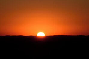 Auringonlasku tasaisella maisemalla, jossa ei ole näkyvissä rakennuksia tai muita maamerkkejä.