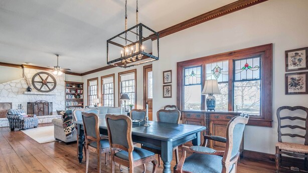 A dining area with a wooden table and chairs, a chandelier, and a fireplace. - Serene Hill Country Wildlife Sanctuary w/ Porch (Boerne)