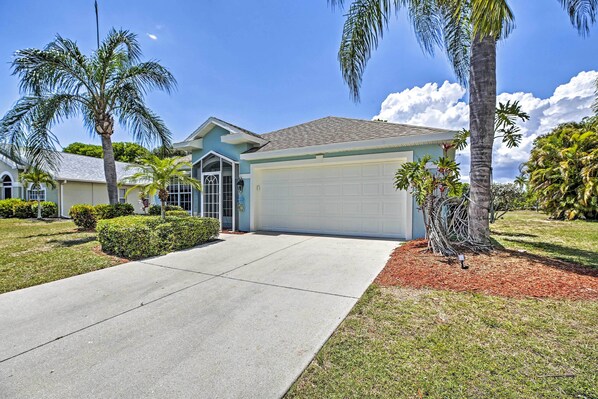 A residential house with a garage, palm trees, and a well-maintained lawn. - Modern Beach Retreat w/ Pool, Hot Tub, & Patio! (Fort Myers)