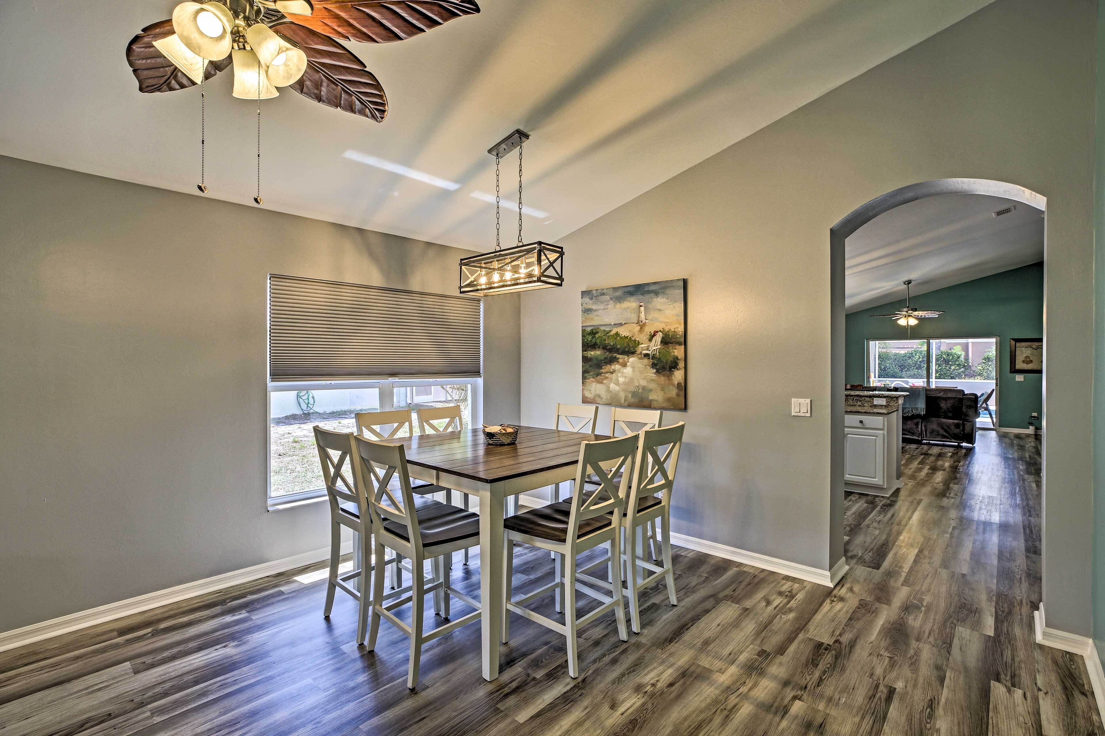 A dining area with a wooden table and chairs, a ceiling fan, and a view through a window.