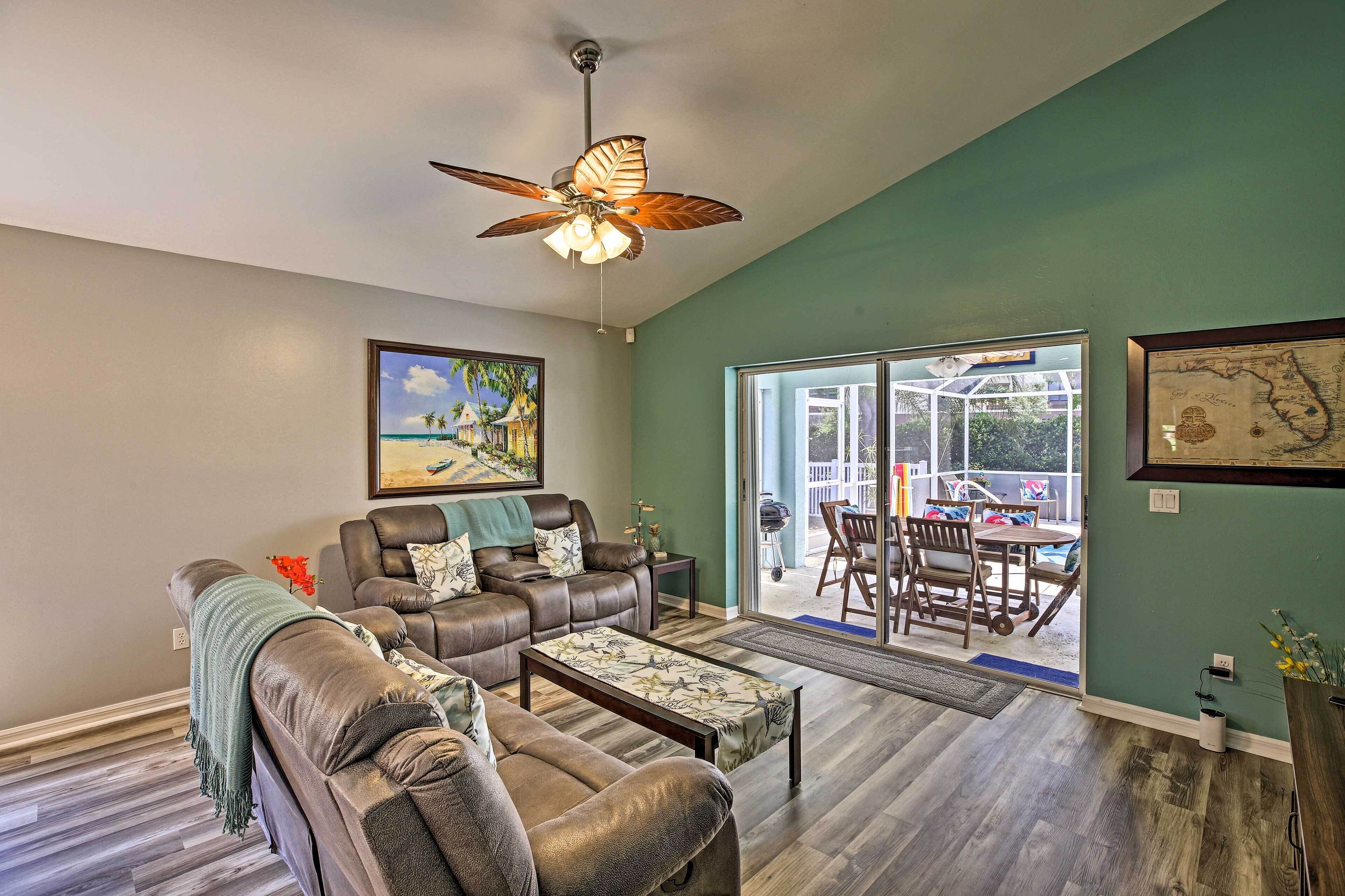 A living room with a ceiling fan, a sofa set, a coffee table, and a large window with a view of the outdoors.