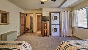 A bedroom with two beds, a ceiling fan, a washing machine, and a television. - Angel Fire Mtn Escape: Walk to Chile Express Lift! (Angel Fire)
