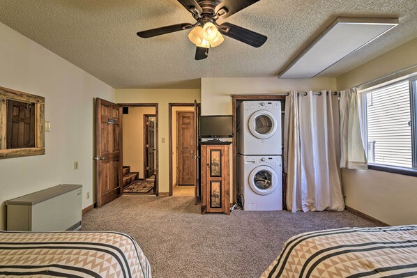 A bedroom with two beds, a ceiling fan, a washing machine, and a television. - Angel Fire Mtn Escape: Walk to Chile Express Lift! (Angel Fire)
