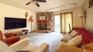 A living room with a fireplace, a ceiling fan, a flat-screen TV, and a sofa. - Angel Fire Mtn Escape: Walk to Chile Express Lift! (Angel Fire)