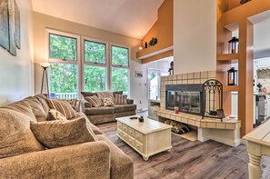 A spacious living room with a fireplace, large windows, and a cozy seating area. - Charming Lake Harmony Townhouse w/ Balcony! (Lake Harmony)