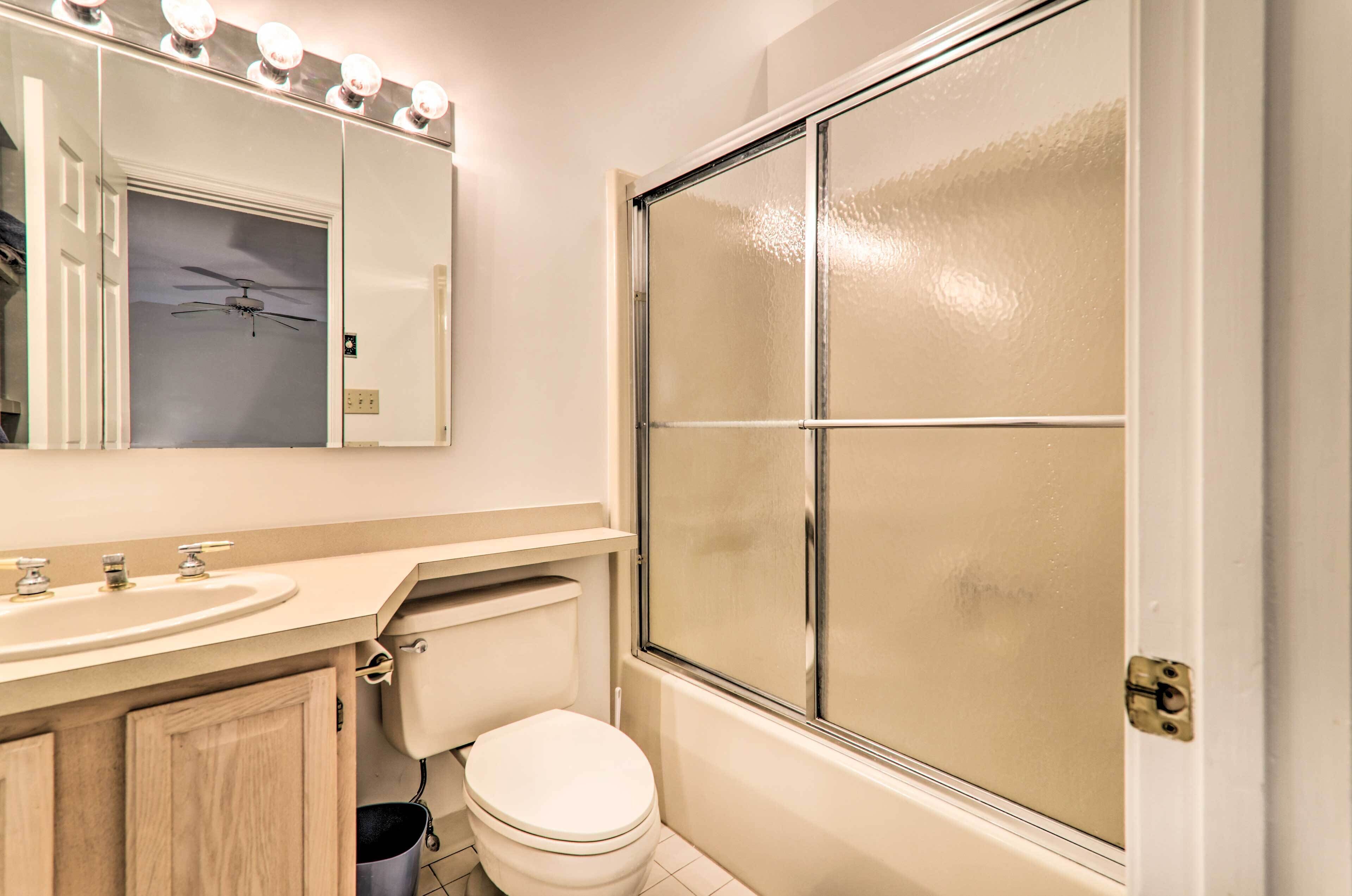 A bathroom with a white sink, mirror, and toilet.