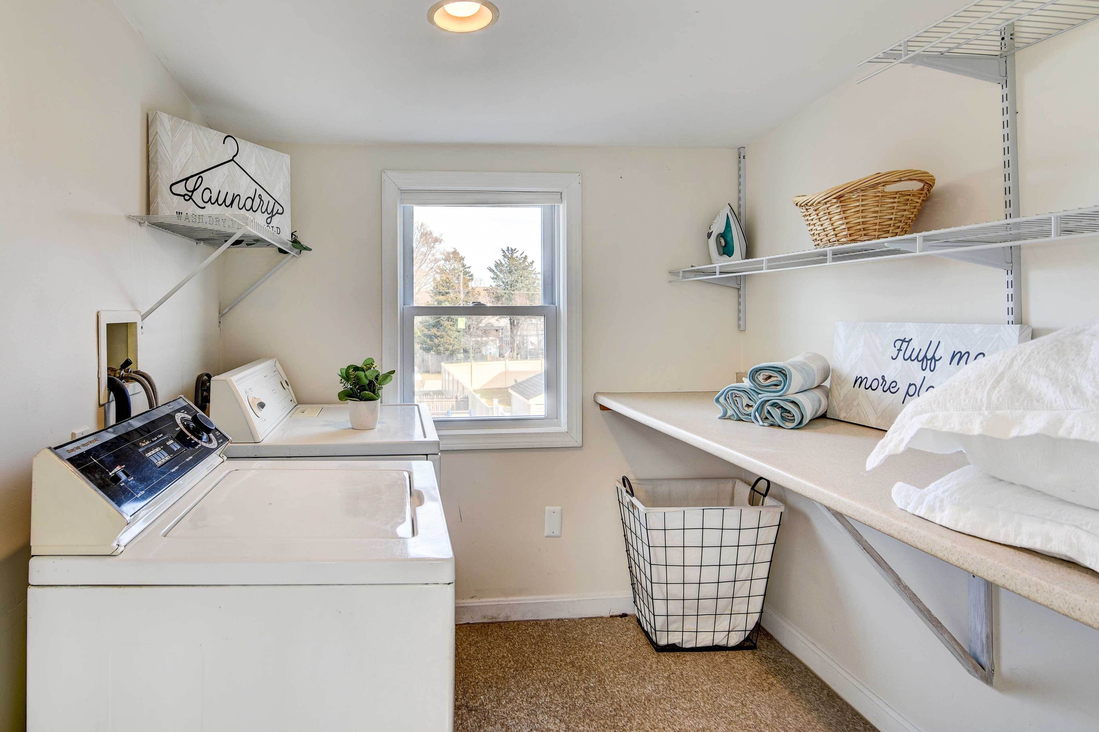 A laundry room with a washing machine, a drying rack, a basket, and a shelf with towels and a sign that says "Laundry".