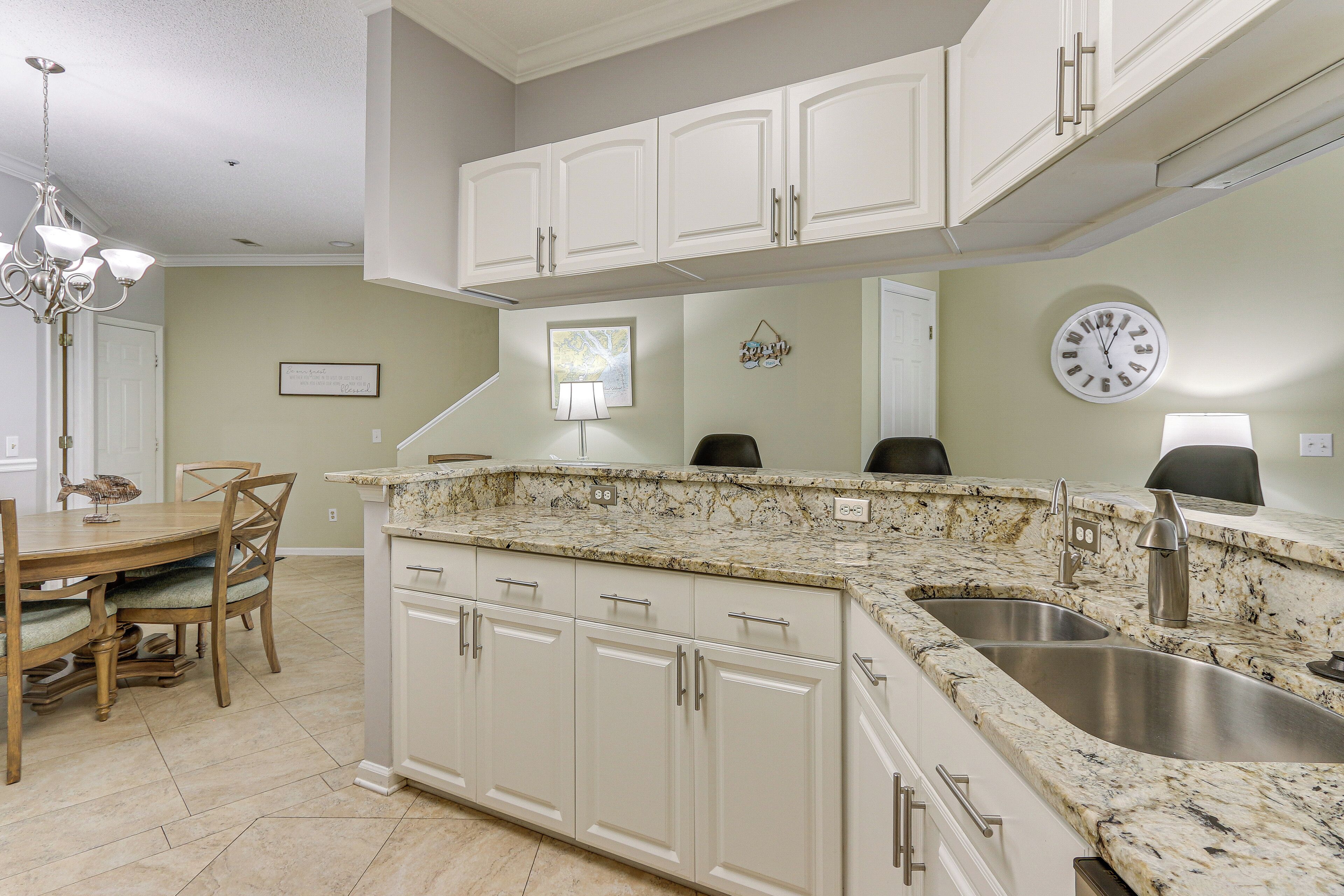 A kitchen with white cabinets, a granite countertop, and a double sink.