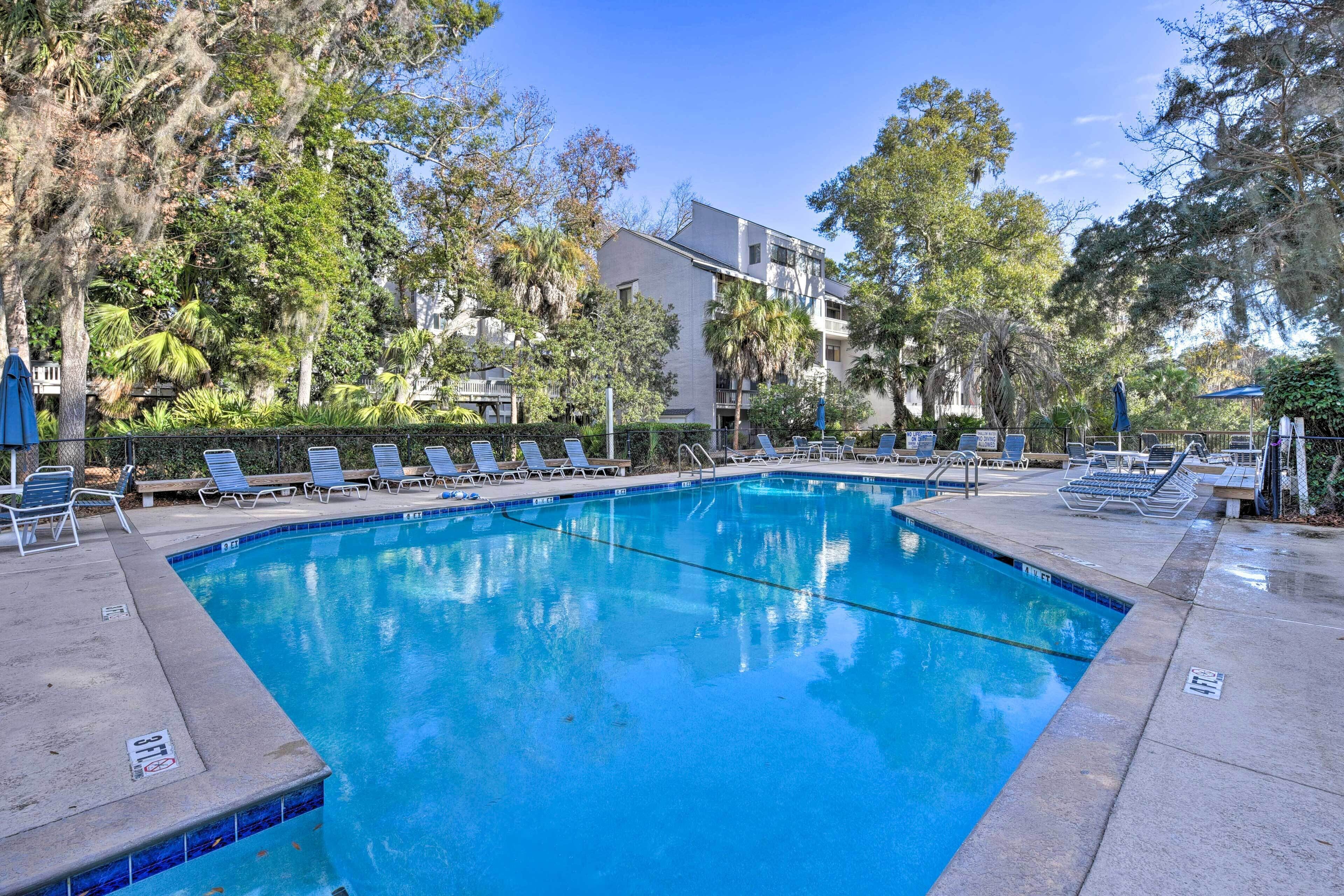 A swimming pool with lounge chairs and a building in the background.