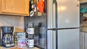 A kitchen with a refrigerator, coffee maker, and a sign that reads "Coffee and Friends." - Cottage With Fire Pit + Deck on The Klamath River! (Hornbrook)