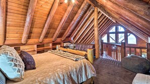 A cozy attic bedroom with a wooden ceiling, a bed with a blanket, pillows, and a wooden railing overlooking a balcony. - Private Eureka Springs Cabin w/ Beaver Lake Views! (Eureka Springs)