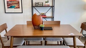 A dining area with a wooden table, cushioned benches, and a modern chandelier.
