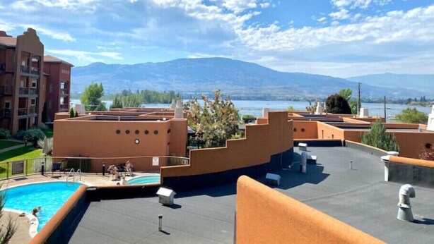 A rooftop pool area with a view of mountains and a lake.