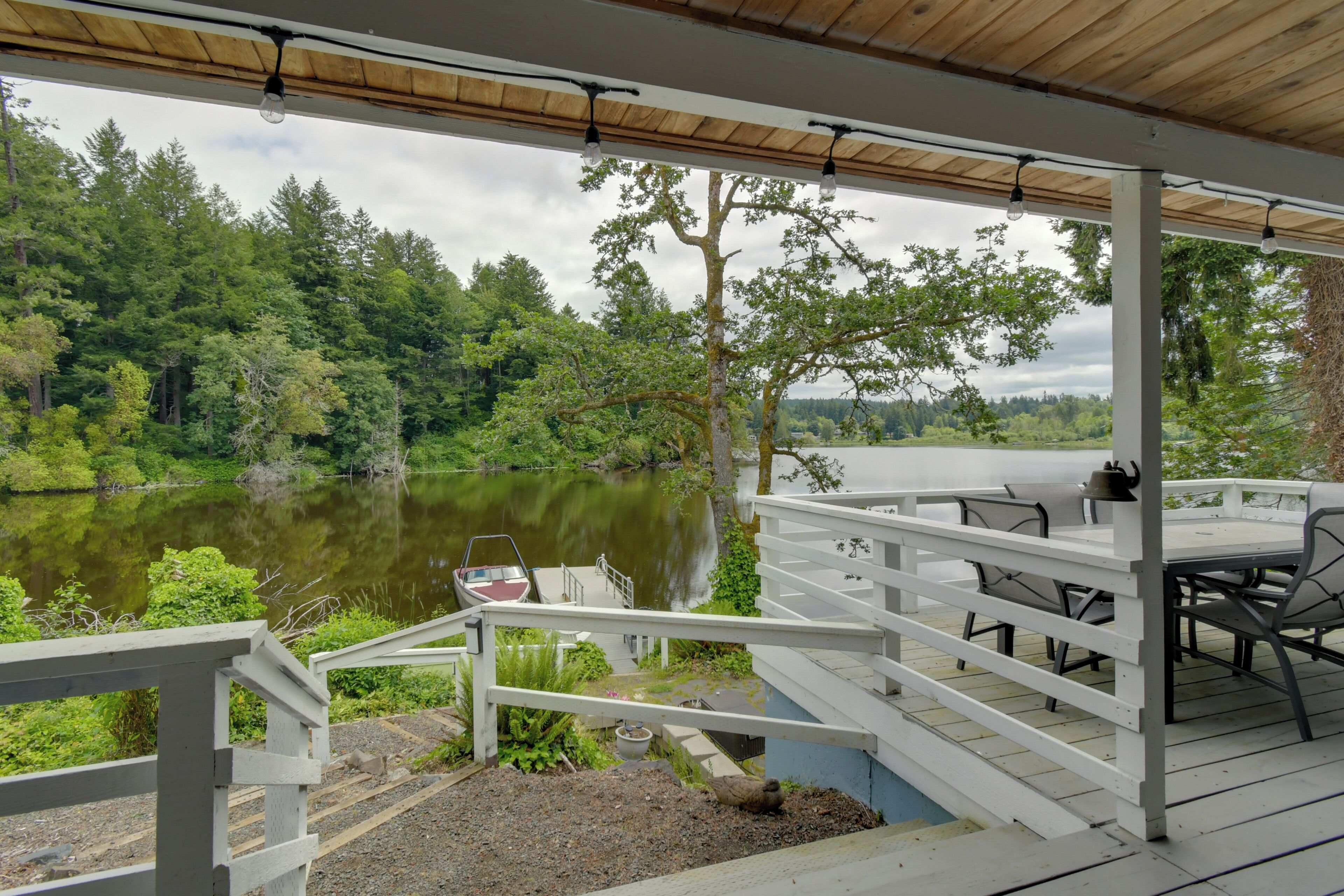 Una terraza techada al aire libre con vista a un lago y un bosque.