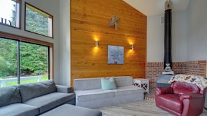 A modern living room with a grey sofa, a red leather chair, and a fireplace. - The Swedish Fish: Getaway on Lake Saint Clair! (Olympia)