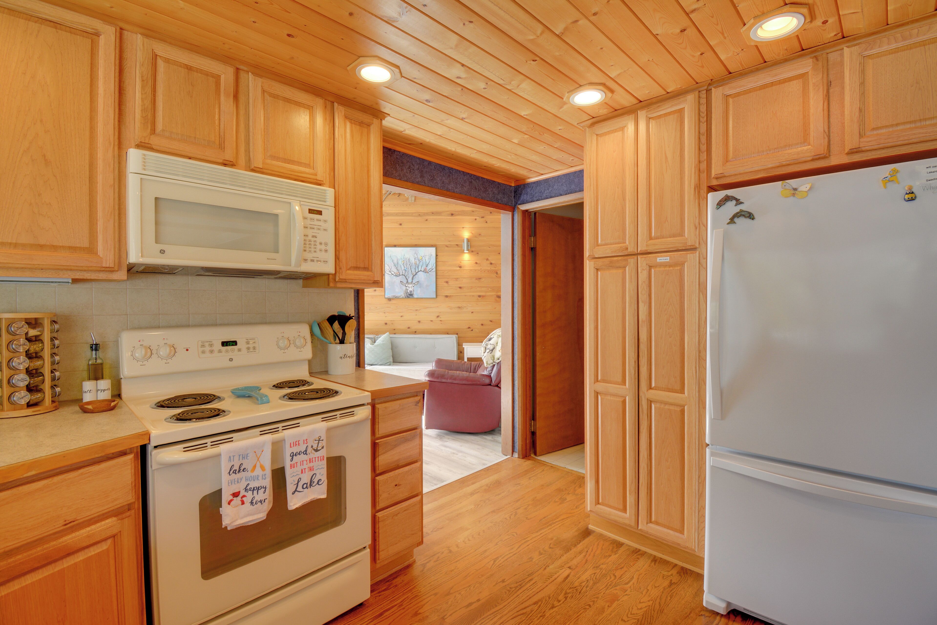 Une cuisine avec des meubles de rangement en bois, une cuisinière blanche et un réfrigérateur.