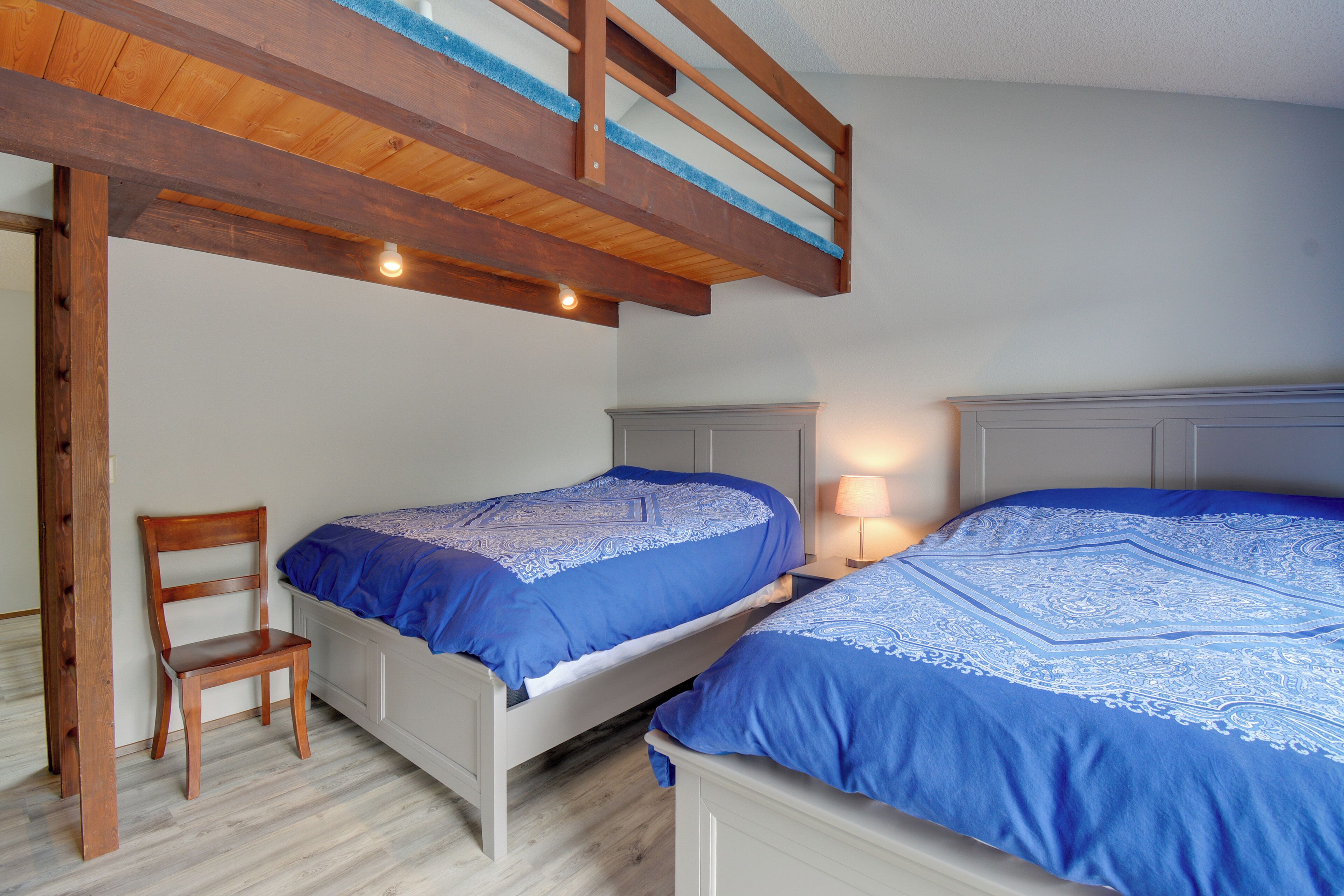 A bedroom with two beds, a wooden chair, and a bunk bed.