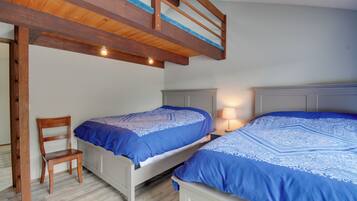 A bedroom with two beds, a wooden chair, and a bunk bed.