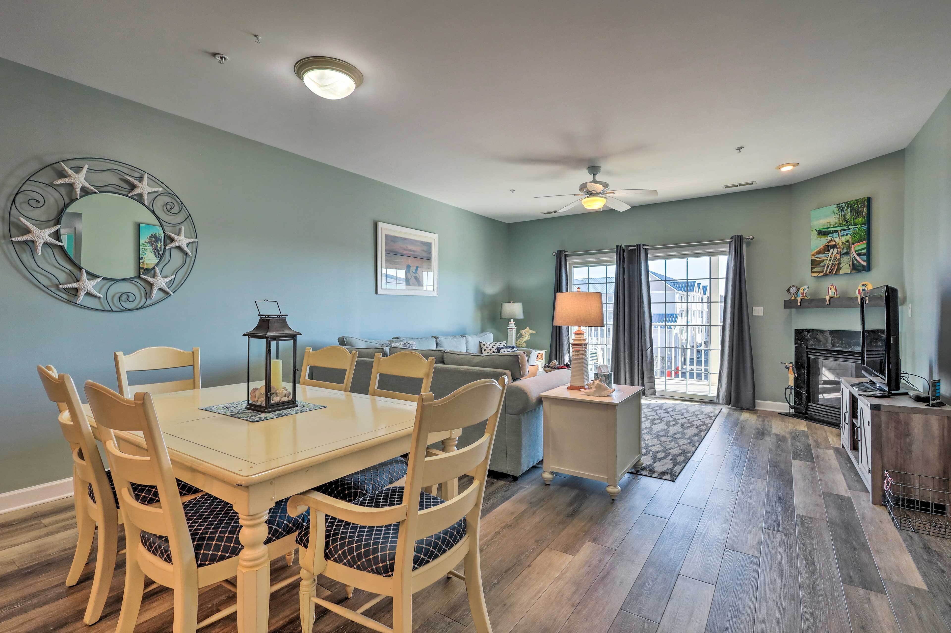 A dining area with a round table and chairs, a ceiling fan, and a fireplace.