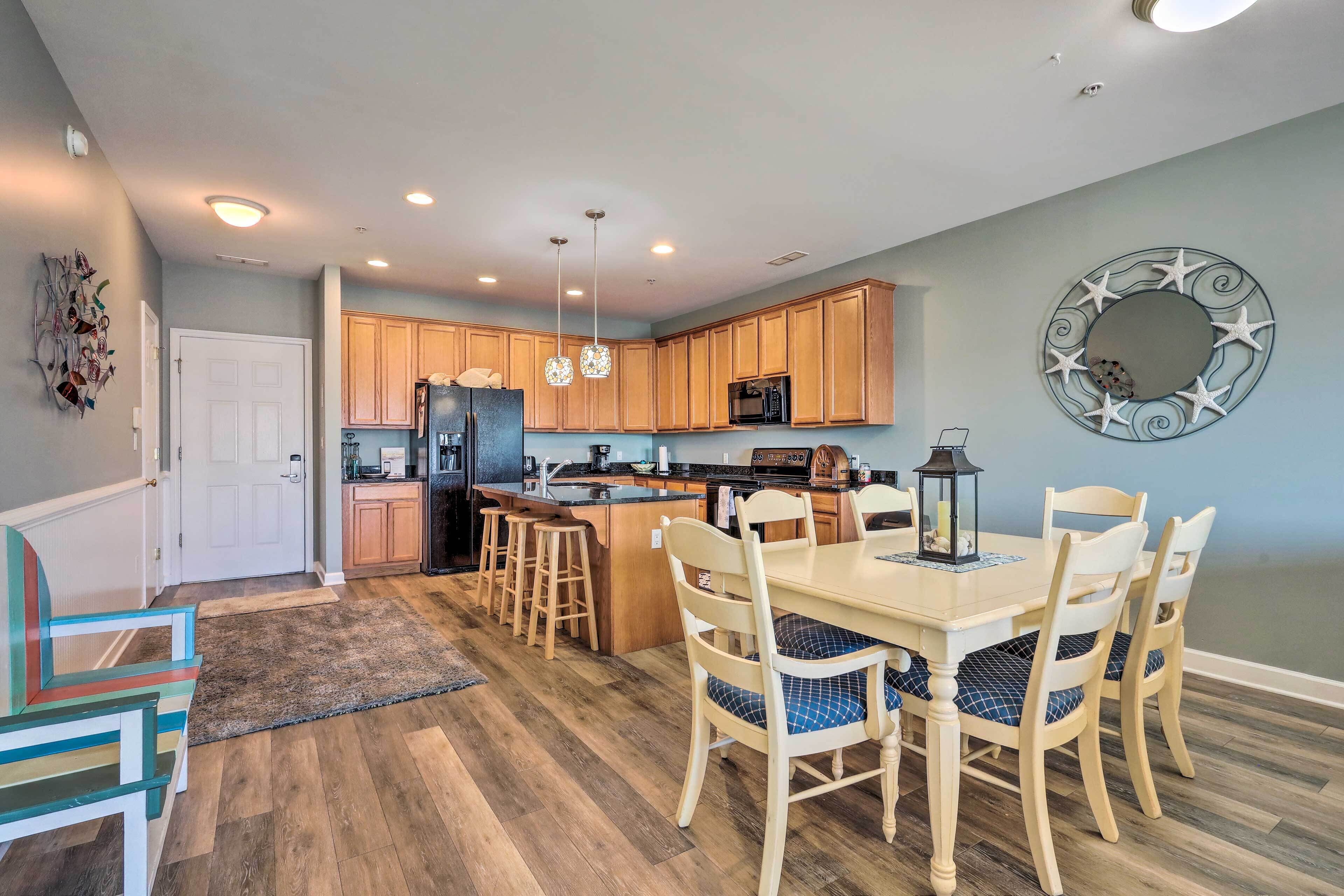 A spacious kitchen with wooden cabinets, a central island, and pendant lighting.