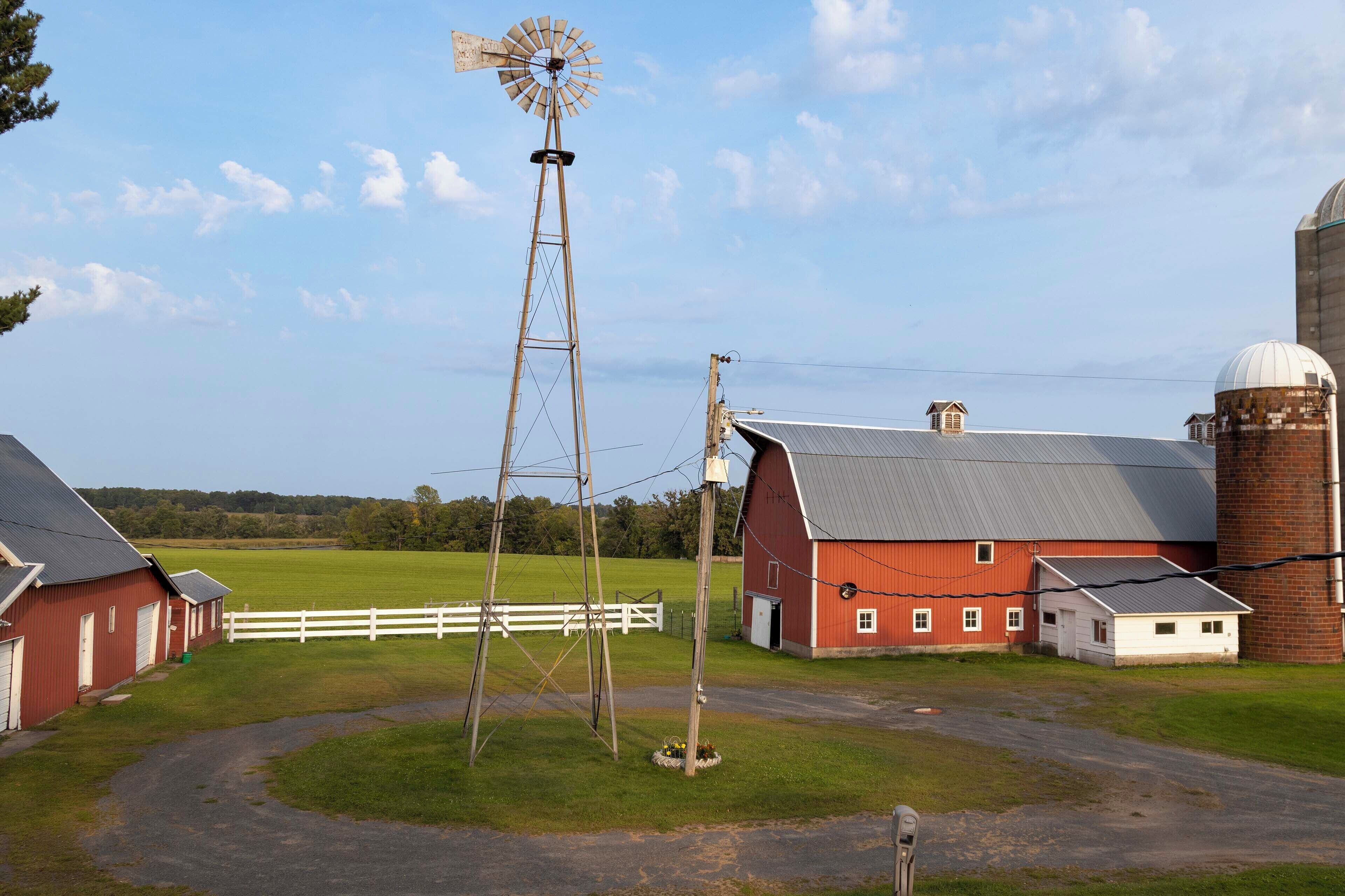 A rural farmstead with a windmill, barns, and a silo.