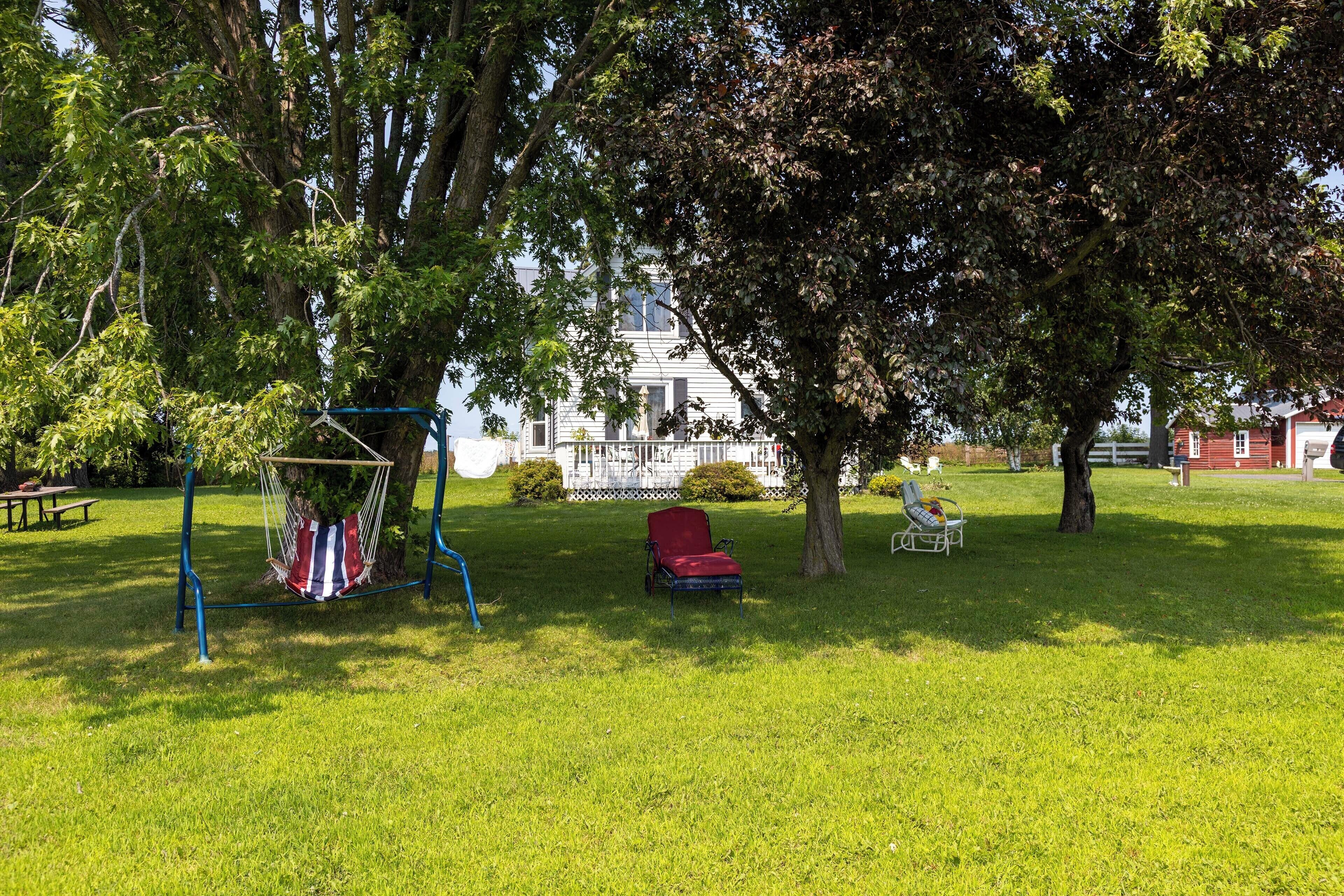 A grassy park area with a swing set, a red chair, and a white chair.