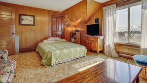 Un dormitorio con cama, cómoda de madera, televisor y ventana con cortinas.