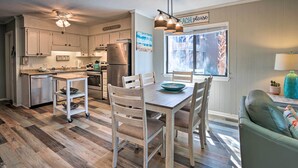A kitchen with wooden cabinets, a stainless steel refrigerator, a dining table with chairs, and a ceiling fan. - Relax by Pool & Walk to Beach: Hilton Head Condo! (Hilton Head Island)