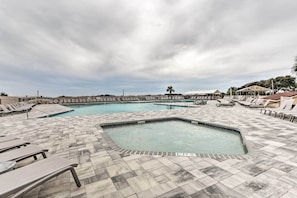 Area piscina con pavimento piastrellato e poltrone da relax.