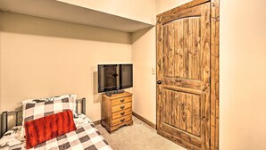 A bedroom with a bed, a television on a wooden dresser, and a wooden door. - Game Room & Fire Pit: Spacious Elk Park Lodge! (Elk Park)