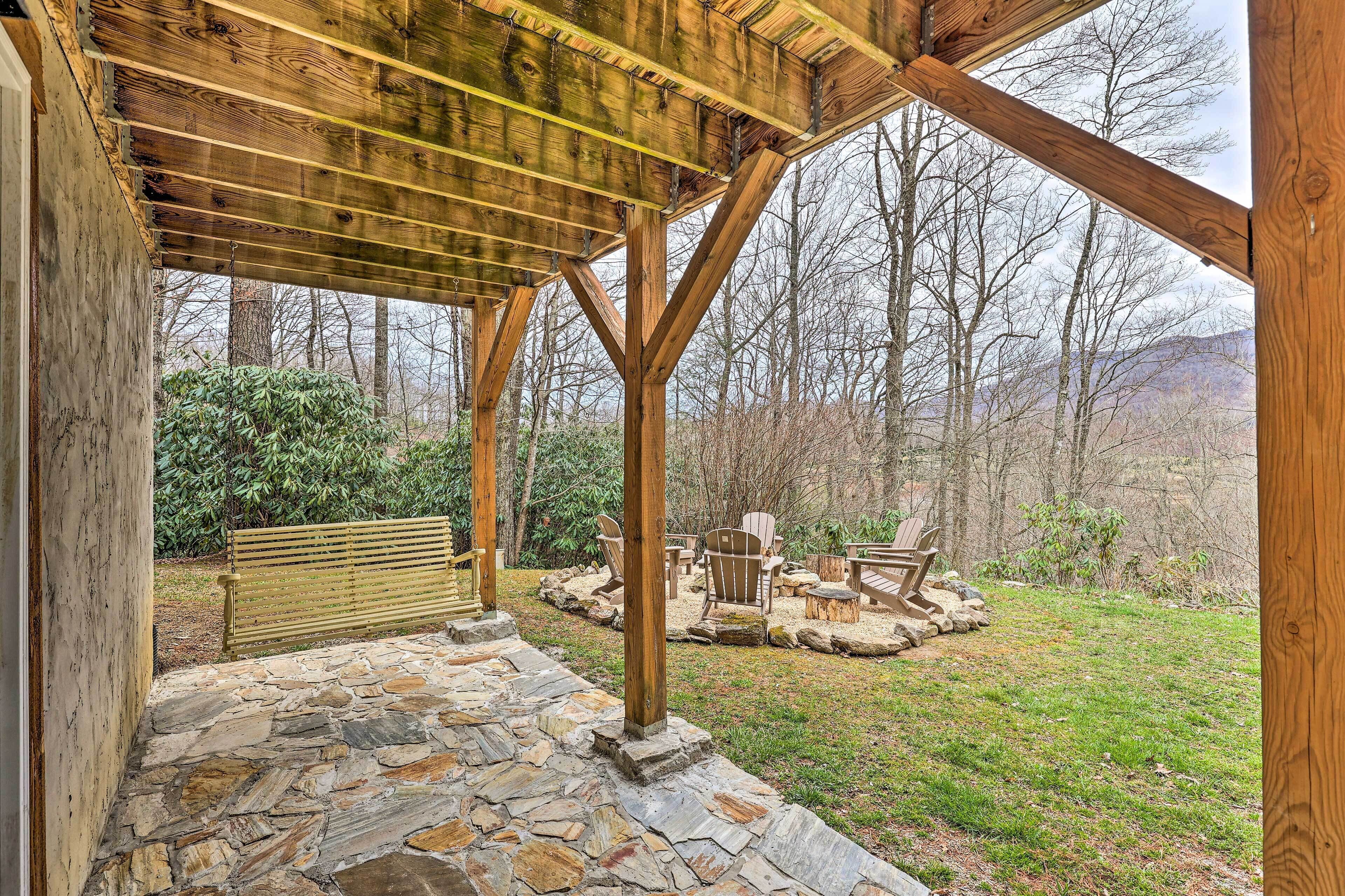 A covered outdoor area with stone flooring, wooden beams, and seating.