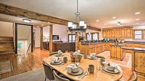 A spacious kitchen with wooden cabinets, a large island, and a dining area with a round table set for four. - Game Room & Fire Pit: Spacious Elk Park Lodge! (Elk Park)