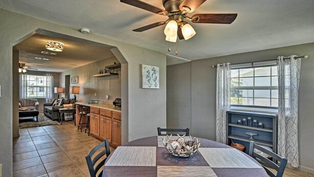 A dining area with a round table, chairs, a ceiling fan, and a view of the kitchen and living room. - Coastal Bungalow 2 Blocks to Ormond Beach! (Ormond Beach)