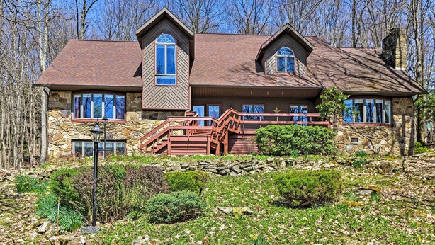 A two-story stone house with a stone facade, a red roof, and a stone staircase leading to the entrance.