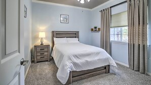 A bedroom with a bed, a nightstand, a ceiling fan, a window with curtains, and a wall-mounted shelf. - Spacious Home w/ Patio: 5 Mi to Memorial Park (Houston)