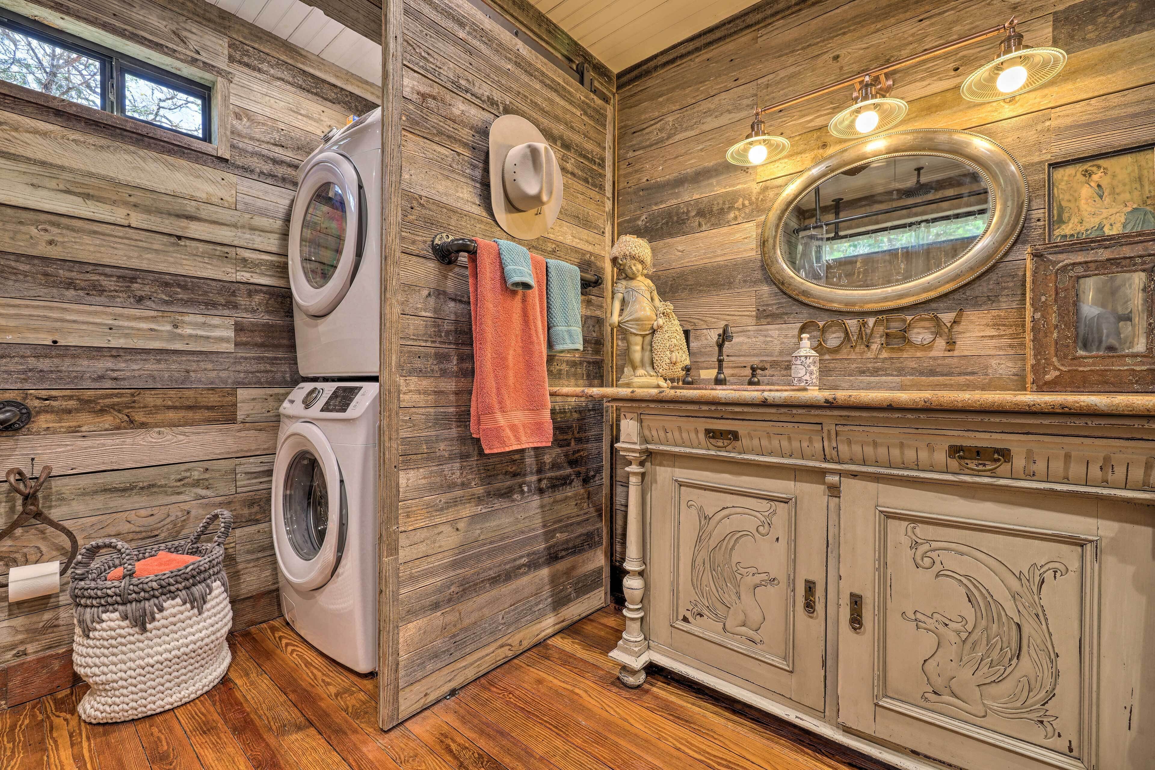 Un baño rústico con paredes de madera, lavadora, tocador con espejo y decoración temática vaquera.