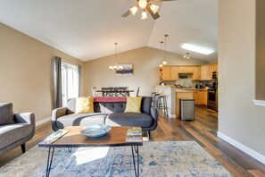 A modern living room with a sofa, coffee table, and a dining area with a chandelier. - Accommodating Anchorage Abode < 1 Mi to Jewel Lake (Anchorage)