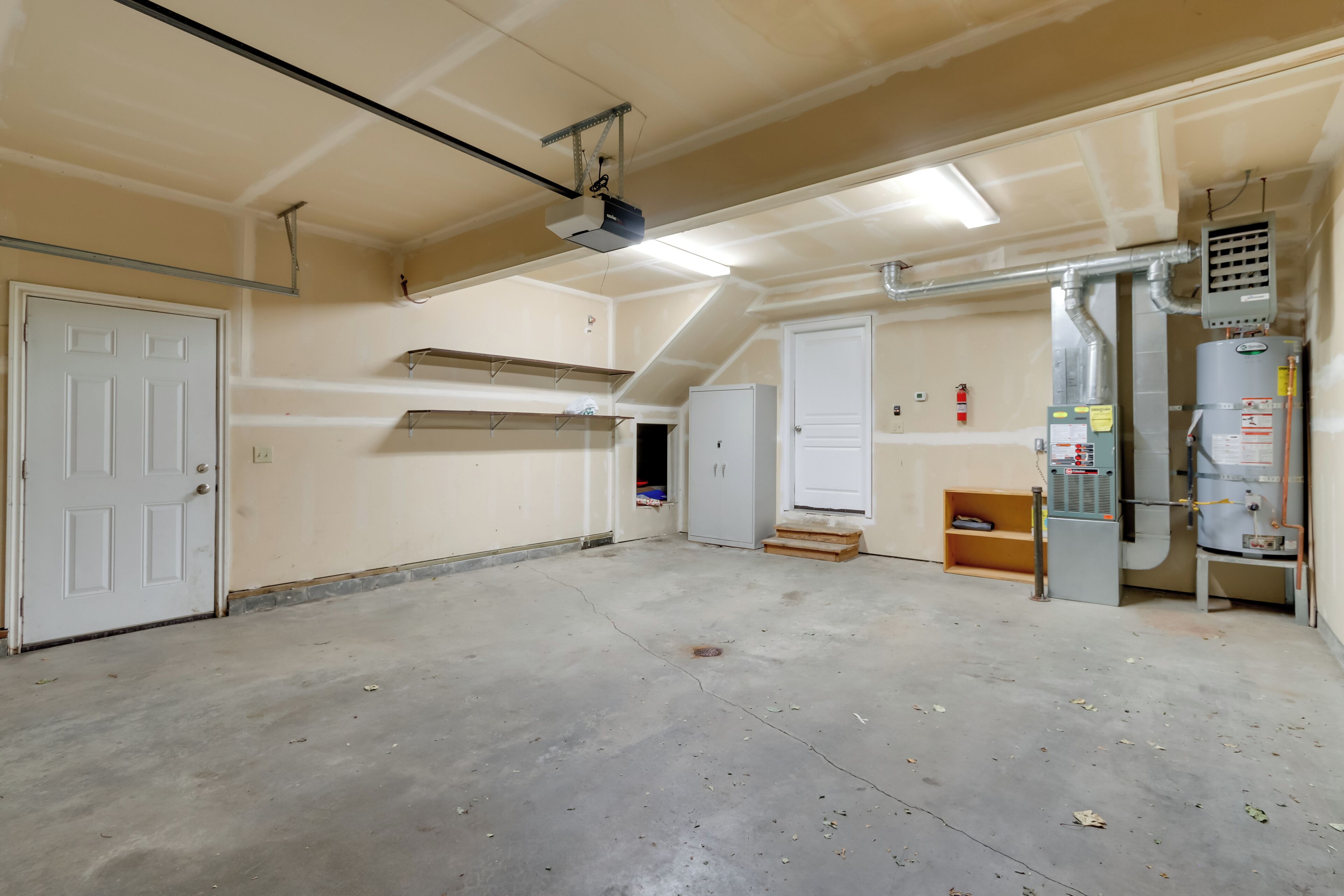 A spacious, unfinished basement with concrete floors, exposed ductwork, and a large water heater.