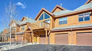 A multi-story wooden building with a covered porch, large windows, and garage doors.