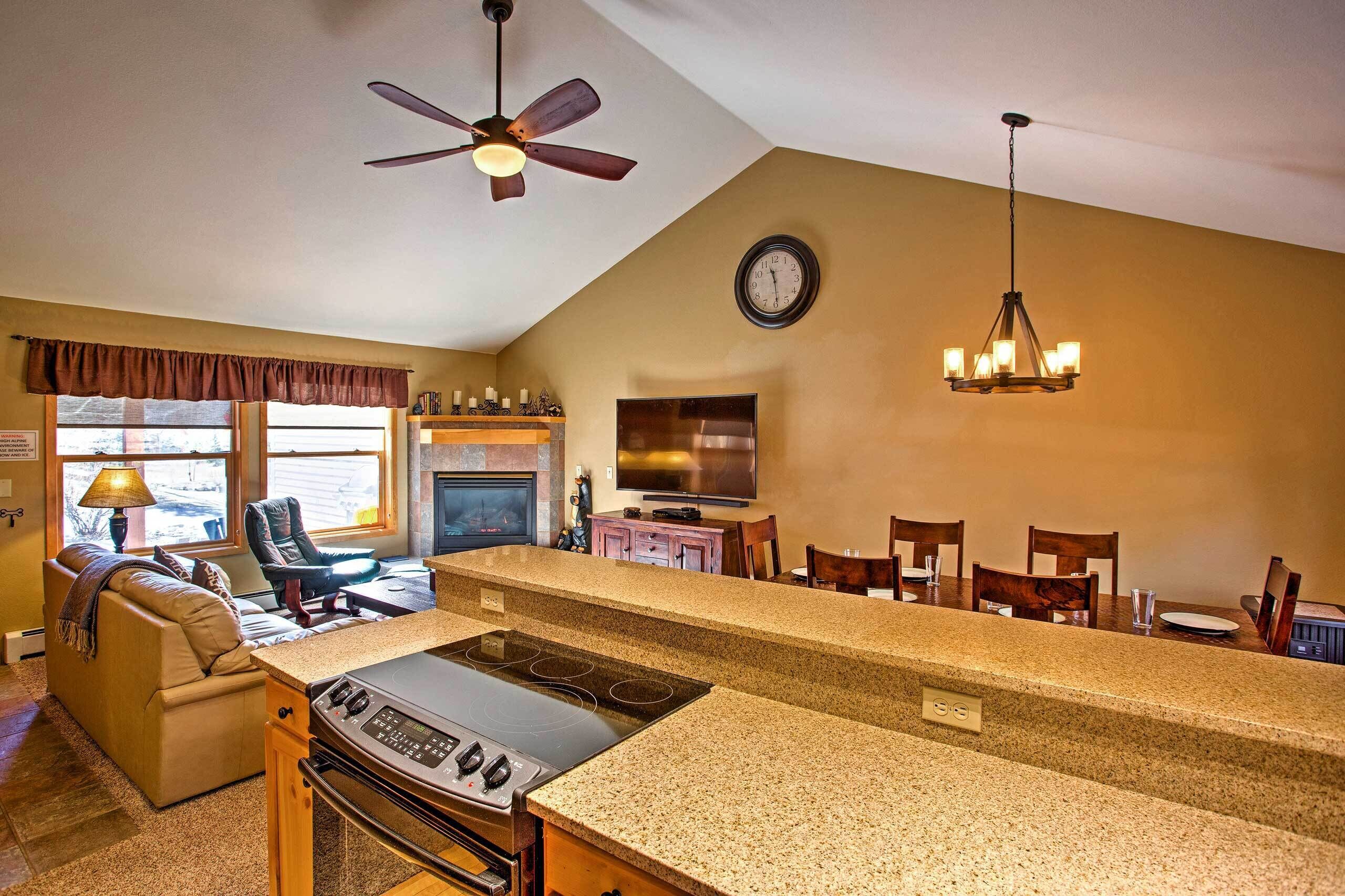 A kitchen with a large island, a dining area, and a living room with a fireplace.