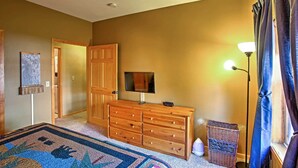 A bedroom with a wooden dresser, a television, a lamp, and a rug.