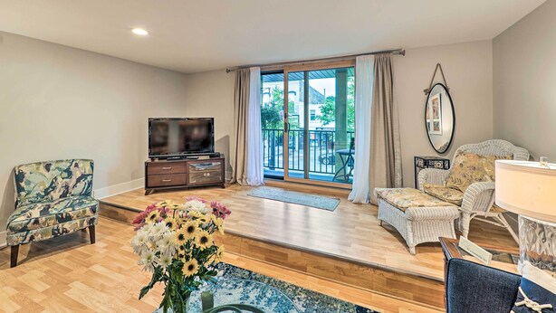 A spacious living room with a wooden floor, a television, a sofa, and a chair. - Downtown Grand Haven Apt < 1 Mi to Lake Michigan (Grand Haven)