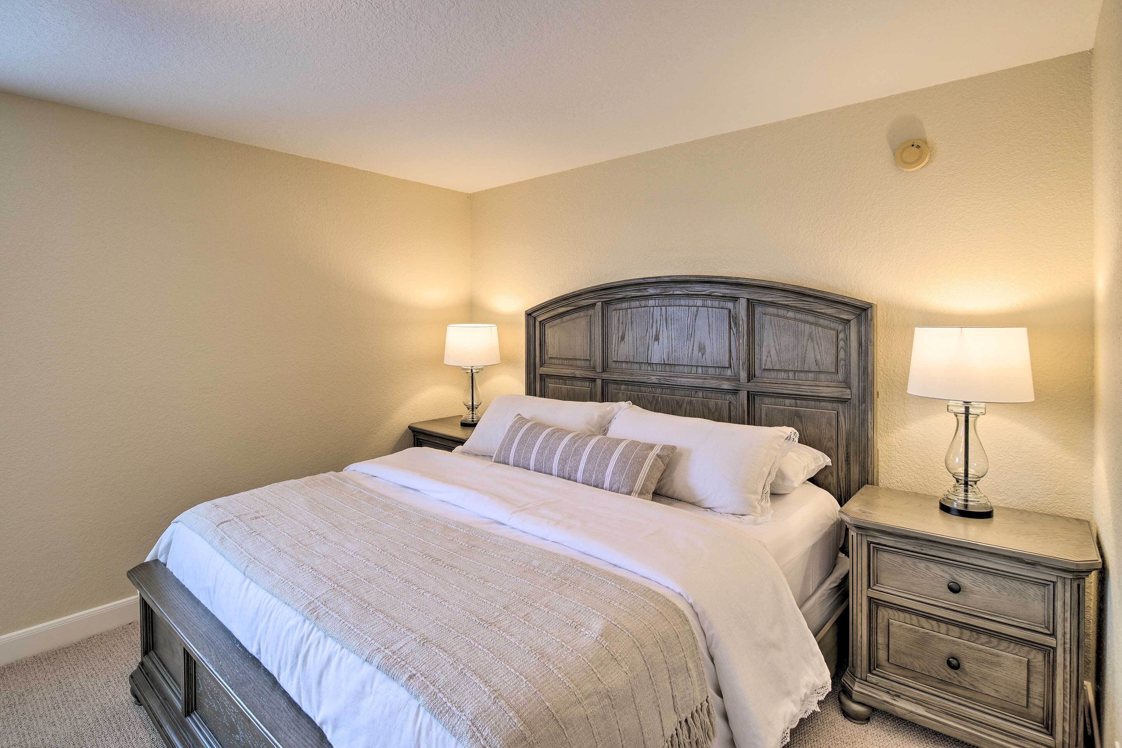 A bedroom with a bed, two bedside tables with lamps, and a headboard.