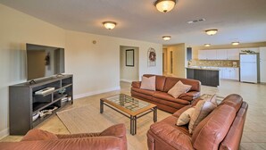 A spacious living room with a brown leather sofa, a glass coffee table, and a dark wooden entertainment unit. - Apt w/ Balconies - Steps to Kemah Boardwalk! (Kemah)