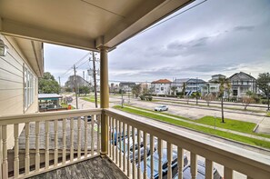 A balcony with a view of a residential street, houses, and parked cars. - Apt w/ Balconies - Steps to Kemah Boardwalk! (Kemah)